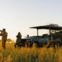 Two people with cameras in front of a 4x4 in the African bush