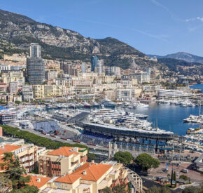 Panoramic view of Monaco cityscape with Port Hercule, luxury yachts, and mountains