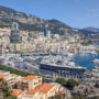 Panoramic view of Monaco cityscape with Port Hercule, luxury yachts, and mountains